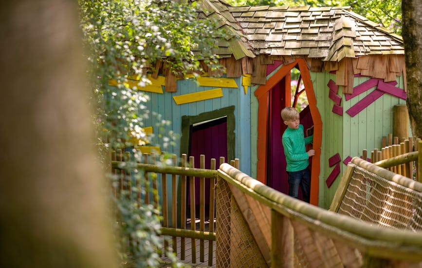 A boy explores BeWILDerville, a colourful wooden treehouse in BeWILDerwood Cheshire