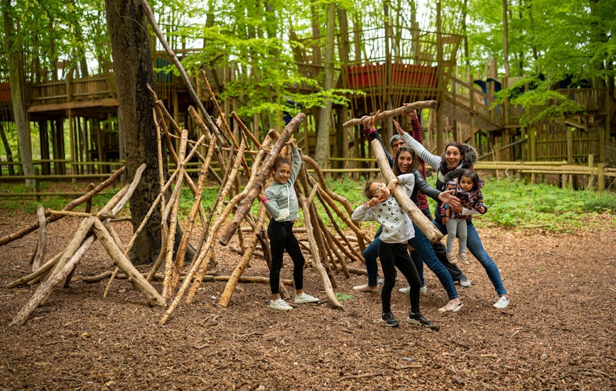A family pose for a photo whilst building a den at BeWILDerwood