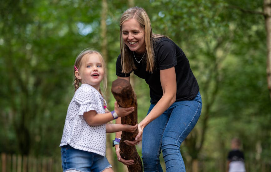 A mother and daughter carry a large stick to build a den