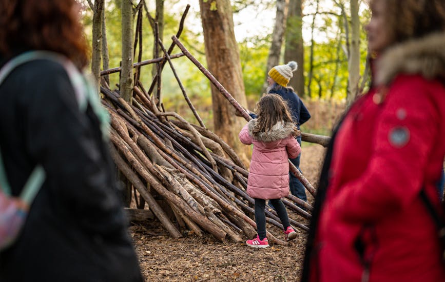 A family build a wooden den together at BeWILDerwood