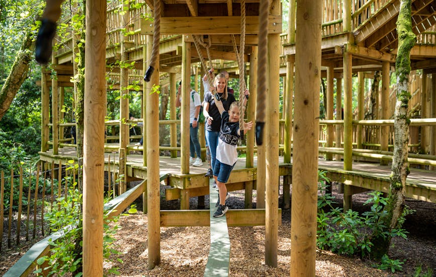 A family cross a narrow path on the Sky Maze at BeWILDerwood