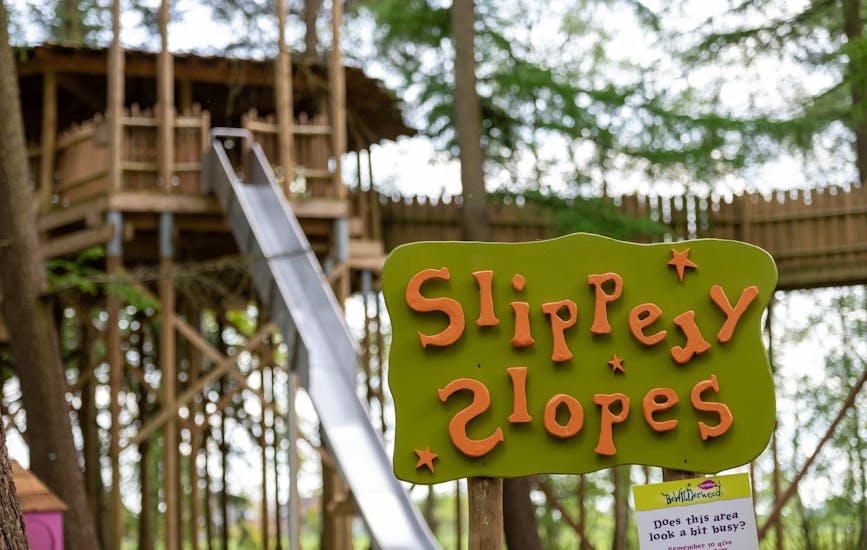 A wooden sign saying Slippery Slopes at BeWILDerwood Cheshire