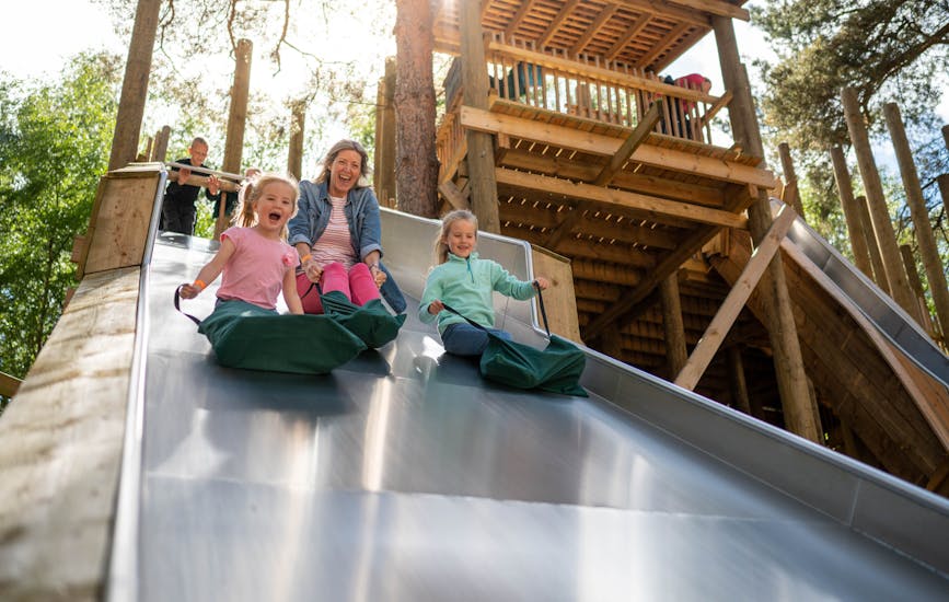 A mother and two daughters slide down the Slippery Slopes at BeWILDerwood