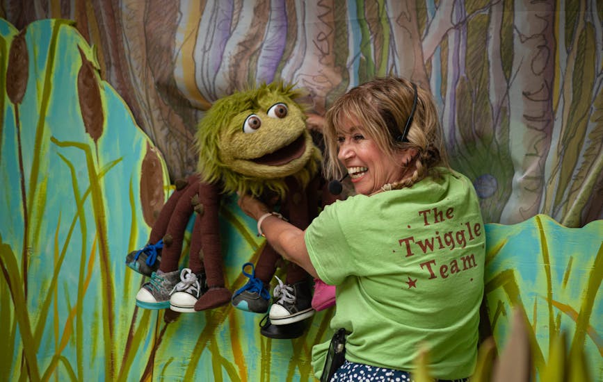 An actor laughs and interacts with a puppet on the Storytelling Stage at BeWILDerwood