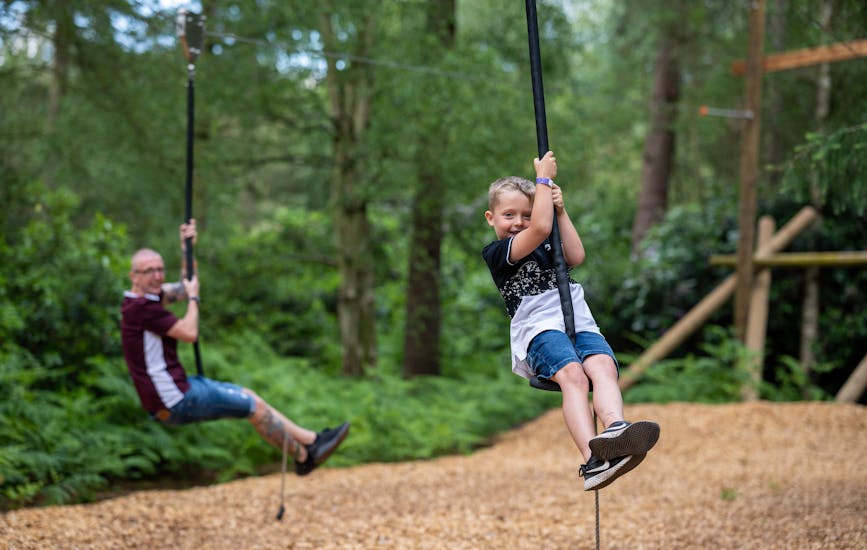 A father and son play on the zip lines at BeWILDerwood