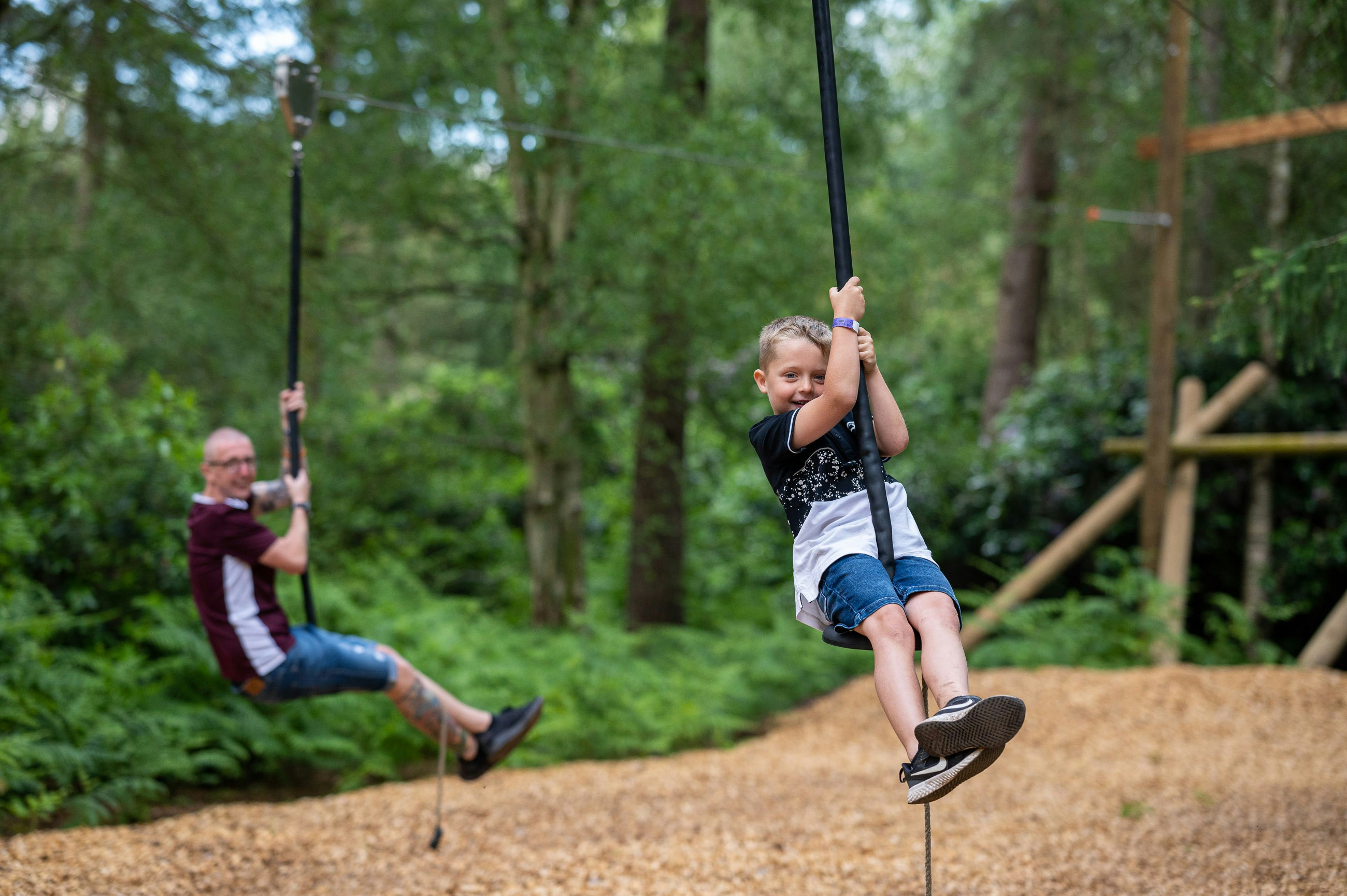 A father and son play on the zip lines at BeWILDerwood