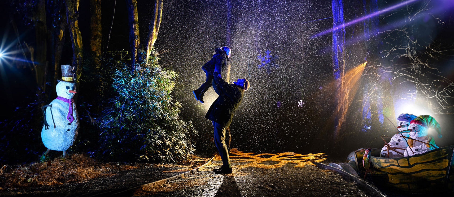 A father and child play in the snow at BeWILDerwood Presents Christmas surrounded by snowmen