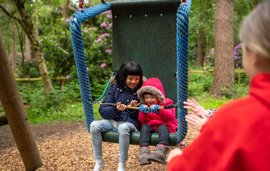 Two children play on a swing together at BeWILDerwood