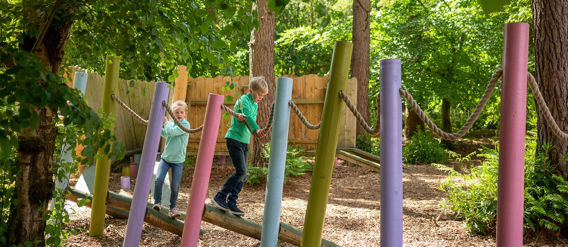 Children play on colourful wooden groundplay at BeWILDerwood