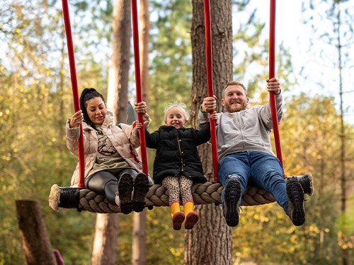 A family play together on a swing during Autumn at BeWILDerwood